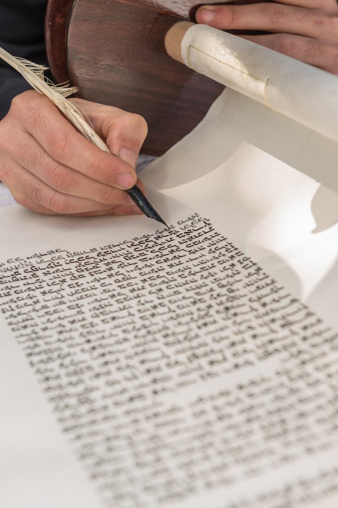 person writing with feather on a scroll